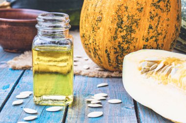 Mavi eski tahtalarda bir kabak yakın bir şişede kabak çekirdeği uçucu yağ.