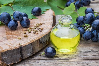 Bir cam şişe üzüm uçucu yağ ve eski ahşap tahtalar üzerinde zar. Mavi üzüm. Spa, eko ürünler konsepti.