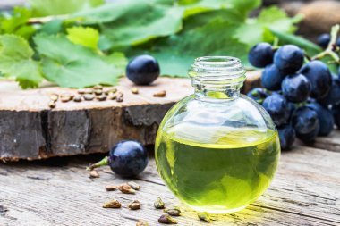 Bir cam şişe üzüm uçucu yağ ve eski ahşap tahtalar üzerinde zar. Mavi üzüm. Spa, eko ürünler konsepti.