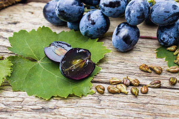 Grapes and grape seeds on a green leaf on old wooden boards. Blue grape. Spa, eco products concept.