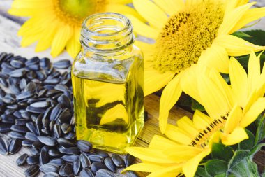 Ahşap bir arka plan üzerinde tohum ve taze çiçekler ile cam bir kavanozda Organik ayçiçek yağı. Sağlıklı gıdalar ve yağlar.
