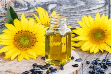 Ahşap bir arka plan üzerinde tohum ve taze çiçekler ile cam bir kavanozda Organik ayçiçek yağı. Sağlıklı gıdalar ve yağlar.