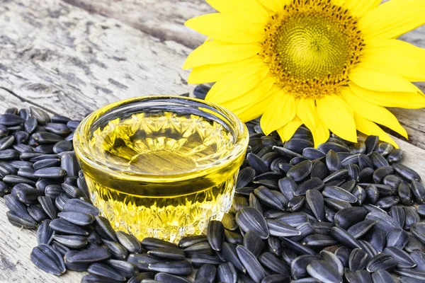 Sunflower oil with seeds on a wooden background near fresh sunflower flowers. Organic and eco food. — Stock Photo, Image