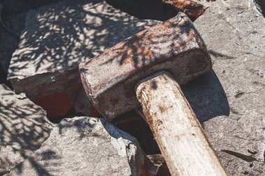 Kırık tuğla ve beton taşlar üzerinde paslı balyoz.