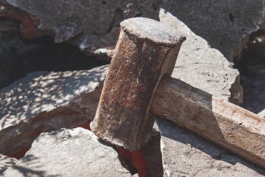 Kırık tuğla ve beton taşlar üzerinde paslı balyoz.