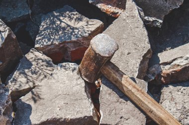 Kırık tuğla ve beton taşlar üzerinde paslı balyoz.