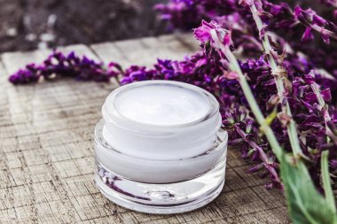 Ahşap bir arka plan üzerinde kozmetik krem ve taze lavanta kır çiçekleri. Yüz kremi.