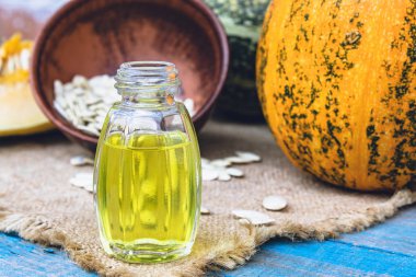 Kabak çekirdeği esansiyel yağı bir şişe yakın çekim çuval ile bir peçete üzerinde.