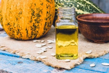 Kabak çekirdeği esansiyel yağı bir şişe yakın çekim çuval ile bir peçete üzerinde.