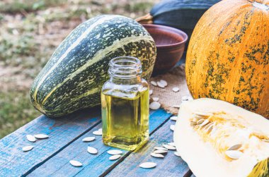 Mavi eski tahtalarda bir kabak yakın bir şişede kabak çekirdeği uçucu yağ.