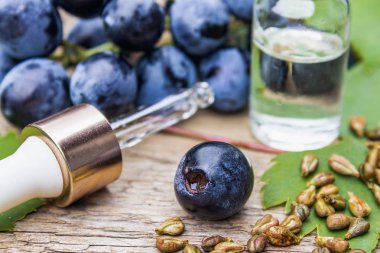 Cam bir kavanozda üzüm çekirdeği yağı ve eski ahşap tahtalar üzerinde taze üzüm. Spa, Eko ürünler konsepti.