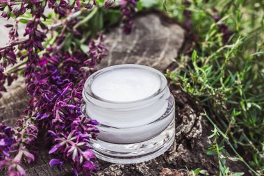 Lavanta kır çiçekleri ile ahşap bir arka plan üzerinde cam bir kavanozda Kozmetik krem. Yüz kremi.