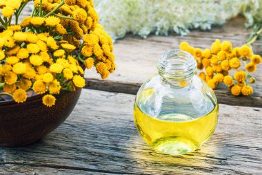 Şifalı otlar tansy ve ahşap bir arka plan üzerinde bir cam şişe de uçucu yağ veya tentür bir kavanoz. Bitkisel ilaç kavramı.