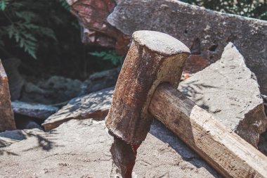 Kırık tuğla ve beton taşlar üzerinde paslı balyoz.