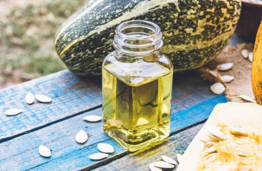 Mavi eski tahtalarda bir kabak yakın bir şişede kabak çekirdeği uçucu yağ.