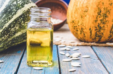 Kabak çekirdeği ve uçucu yağ mavi eski panoları kabak yakın bir şişede.