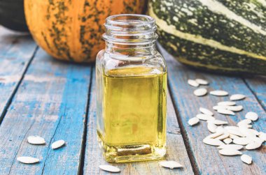 Kabak çekirdeği ve uçucu yağ mavi eski panoları kabak yakın bir şişede.