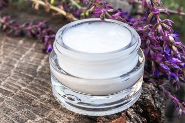 Ahşap bir arka plan üzerinde mavi lavanta kır çiçekleri ile yüz ve el kremi. Yüz kremi.