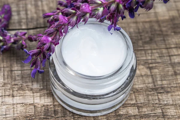 Natural face cream with blue lavender wildflowers on a wooden background. Face cream.