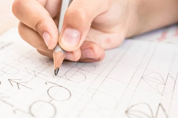 Colegial escribiendo de cerca. Lápiz en la mano de los niños . — Foto de Stock