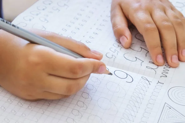 School jongen schrijven nummers close-up. Potlood in de handen van kinderen. — Stockfoto