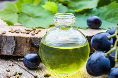 Bir cam şişe üzüm uçucu yağ ve eski ahşap tahtalar üzerinde zar. Mavi üzüm. Spa, eko ürünler konsepti.