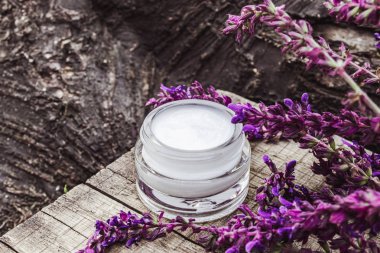 Lavanta kır çiçekleri ile ahşap bir arka plan üzerinde cam bir kavanozda Kozmetik krem. Yüz kremi.