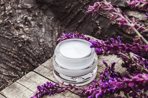 Lavanta kır çiçekleri ile ahşap bir arka plan üzerinde cam bir kavanozda Kozmetik krem. Yüz kremi.