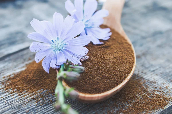 Kék cikória virág és egy fakanállal cikória por egy régi fából készült asztal. Cikória por. A koncepció az egészséges táplálkozás ital. — Stock Fotó