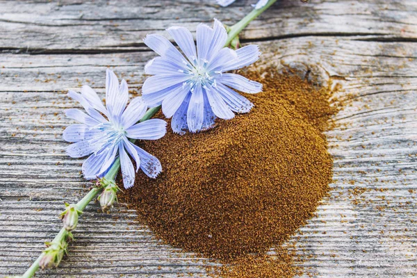 Fiore di cicoria blu e una pila di cicoria in polvere istantanea su un vecchio tavolo di legno. Polvere di cicoria. Il concetto di sano mangiare una bevanda . — Foto Stock
