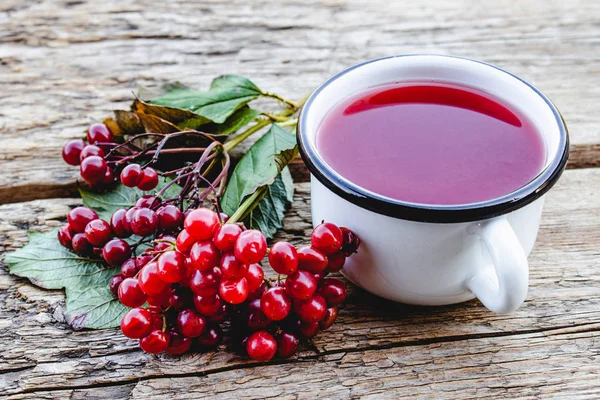 Kırmızı viburnum meyveleri yanında ahşap bir masada beyaz kupa veya sıcak viburnum çay fincan. Doğal vitaminlerin kaynağı. Halk hekimliğinde kullanılır.