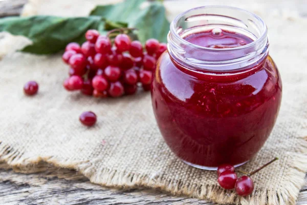 Ahşap bir masa üzerinde taze viburnum meyveleri ile ev yapımı viburnum reçel cam kavanoz. Doğal vitaminlerin kaynağı. Halk hekimliğinde kullanılır. — Stok fotoğraf