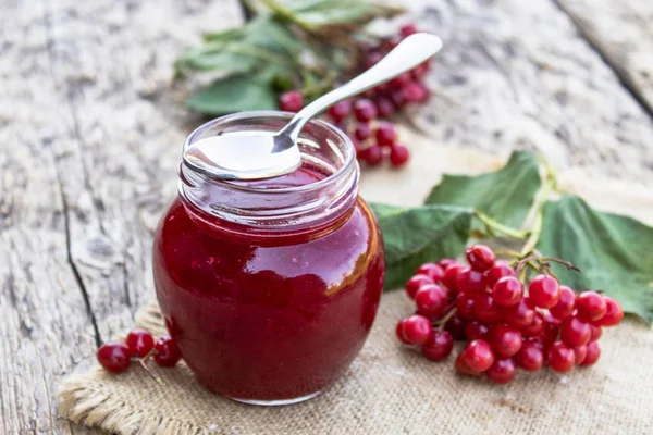 Ahşap bir masa üzerinde taze viburnum meyveleri ile ev yapımı viburnum reçel cam kavanoz. Doğal vitaminlerin kaynağı. Halk hekimliğinde kullanılır.
