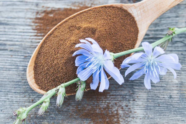 青いチコリの花と古い木製のテーブルの上にチコリパウダーの木製のスプーン。チコリパウダー健康的なダイエットドリンクの概念. — ストック写真