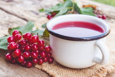 Kırmızı viburnum meyveleri yanında ahşap bir masada beyaz kupa veya sıcak viburnum çay fincan. Doğal vitaminlerin kaynağı. Halk hekimliğinde kullanılır.