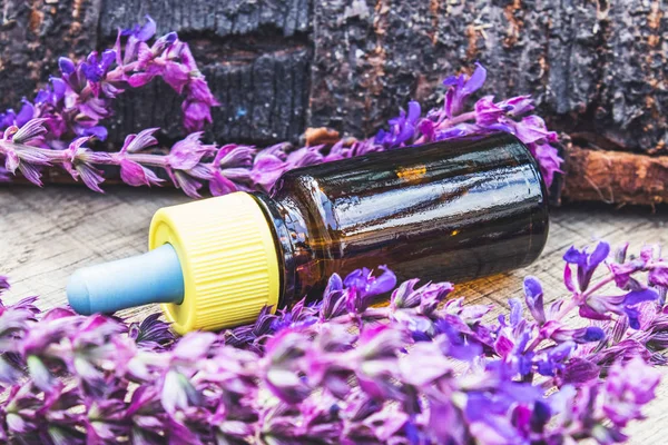 Lavendelöl in einer Glasflasche und Lavendelfarben auf rustikalem Holzgrund. Tinktur oder ätherisches Öl mit Lavendel. pflanzliche Medizin. — Stockfoto