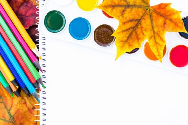 Renkli sonbahar yaprakları, çok renkli kalemler ve yazı için yeri olan beyaz kağıdın yanında resim yapmak için boya. Sonbahar yapraklı arka plan. Yazı için alanı kopyala.