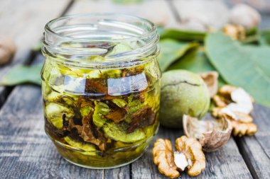 Eski ahşap bir masanın ceviz çekirdeğinin yanındaki kavanozda ceviz olan tentür ya da iksir..