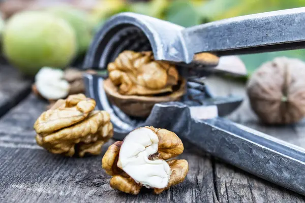 Nueces y nueces se encuentran en una mesa de madera rústica cerca del cascanueces. Núcleos de nueces . —  Fotos de Stock