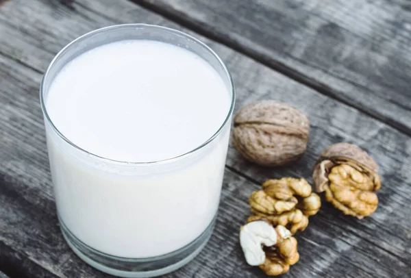 Un vaso de leche blanca y nueces sobre una vieja mesa de madera. Leche vegana de nueces. Alimentos ecológicos . — Foto de Stock