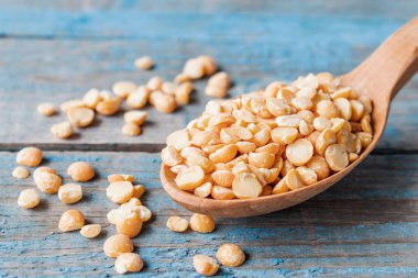 Tahta bir kaşıkta eski tahtalarda kuru, sarı bezelyeler. Kırık bezelyeler yemek pişirmek için kullanılır..