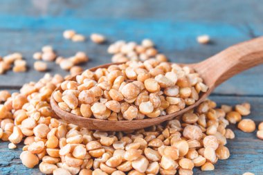 Tahta bir kaşıkta eski tahtalarda kuru, sarı bezelyeler. Kırık bezelyeler yemek pişirmek için kullanılır..