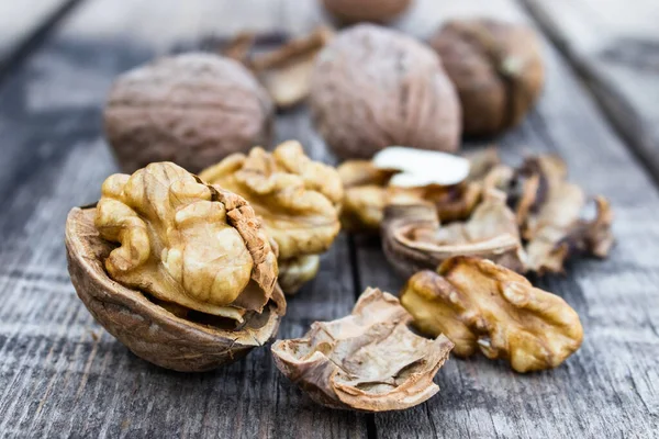 Nueces peladas y nueces se encuentran en una mesa rústica de madera vieja . —  Fotos de Stock