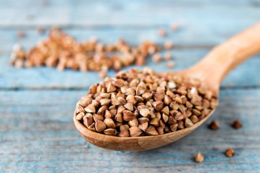 Eski mavi tahtalarda kaşık içinde pişmemiş karabuğday. Karabuğday yemek pişirmek için kullanılır..