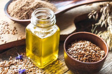 Keten tohumu yağı eski tahtaların arka planında keten tohumlarının yanında bir kavanozda. Keten tohumu yağı yemek, ilaç ve kozmetolojide kullanılır..