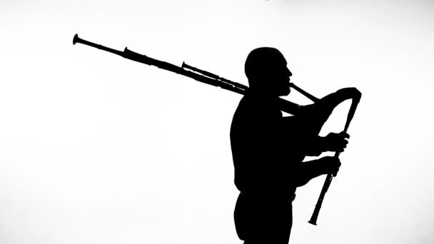 バグパイプを演奏する白い背景の男に黒いシルエット 国民的な民族楽器クローズアップ — ストック動画