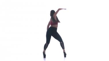 Genç ve güzel bir kız beyaz arka planda modern dans ediyor, plastikleri soyuyor.