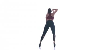 Genç ve güzel bir kız beyaz arka planda modern dans ediyor, plastikleri soyuyor.