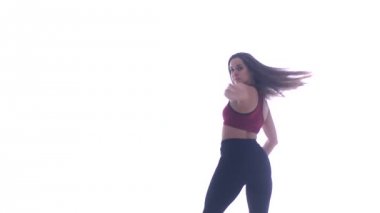 Genç ve güzel bir kız beyaz arka planda modern dans ediyor, plastikleri soyuyor.