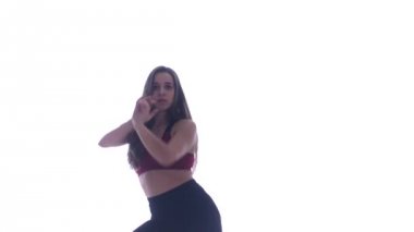 Genç ve güzel bir kız beyaz arka planda modern dans ediyor, plastikleri soyuyor.